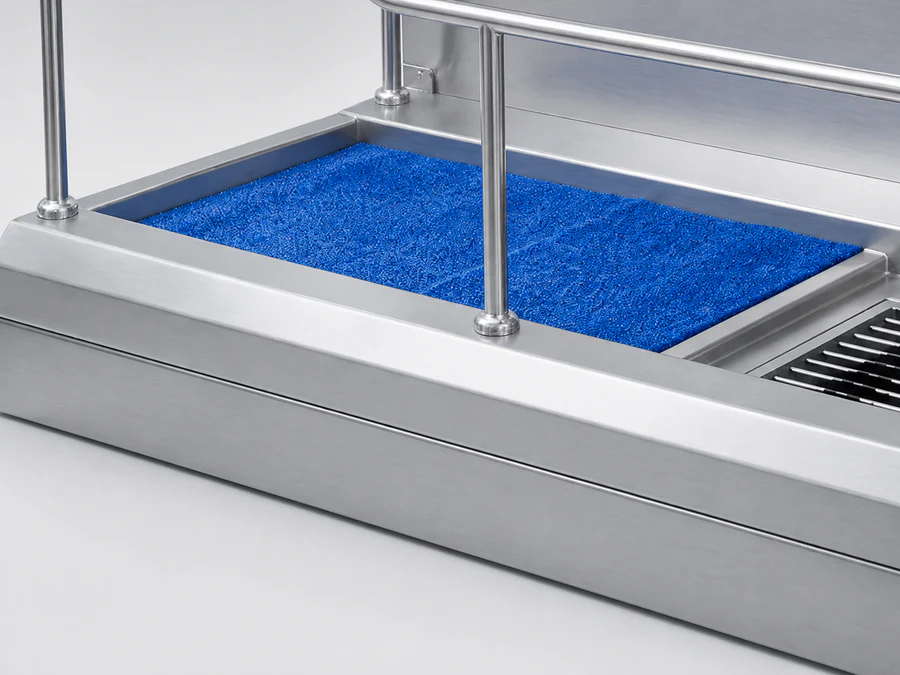 A blue moisture-removal mat beside the brushes on a hygiene station platform
