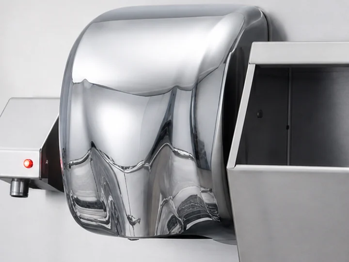 A hand dryer with a stainless steel housing mounted on a hygiene station
