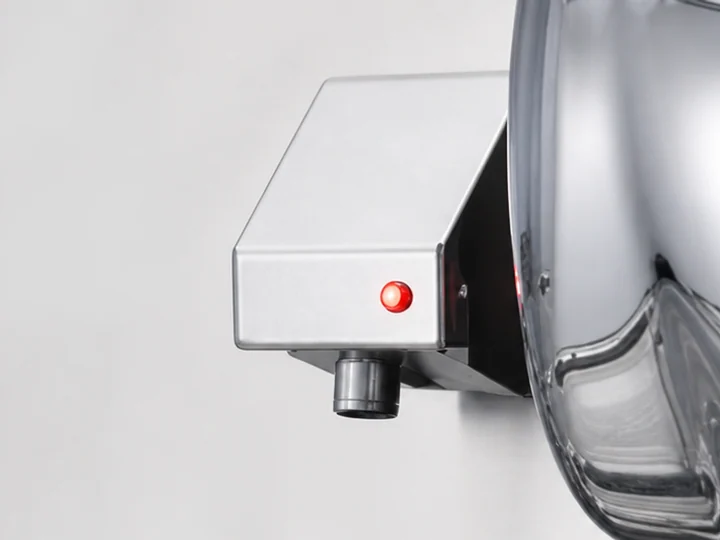 A liquid soap dispenser with a red sensor indicator and stainless steel housing
